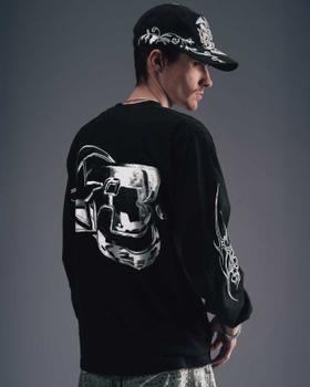 A man wearing a black Greedy Unit long-sleeve tee and printed cap, photographed from behind
