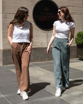Two women wearing Halara wide-leg trousers with fitted white tops on a city sidewalk