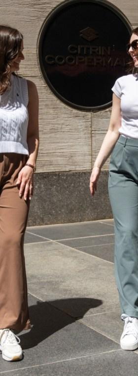 Two women wearing Halara wide-leg trousers with fitted white tops on a city sidewalk