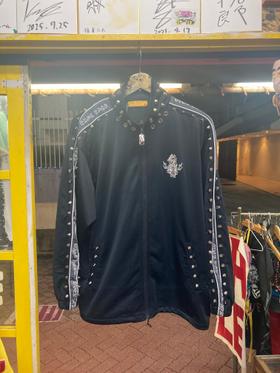 Studded black track jacket hung at the shop entrance, with signed boards and yellow shop fittings around it