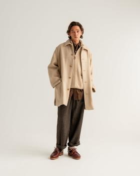 A man wearing a cream HERILL wool overcoat with brown flannel trousers