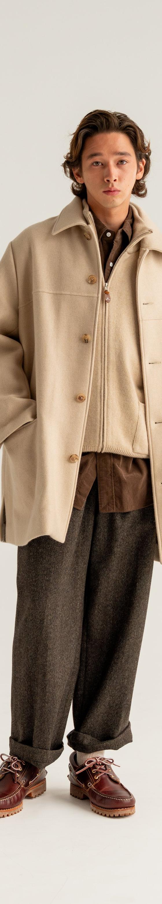 A man wearing a cream HERILL wool overcoat with brown flannel trousers