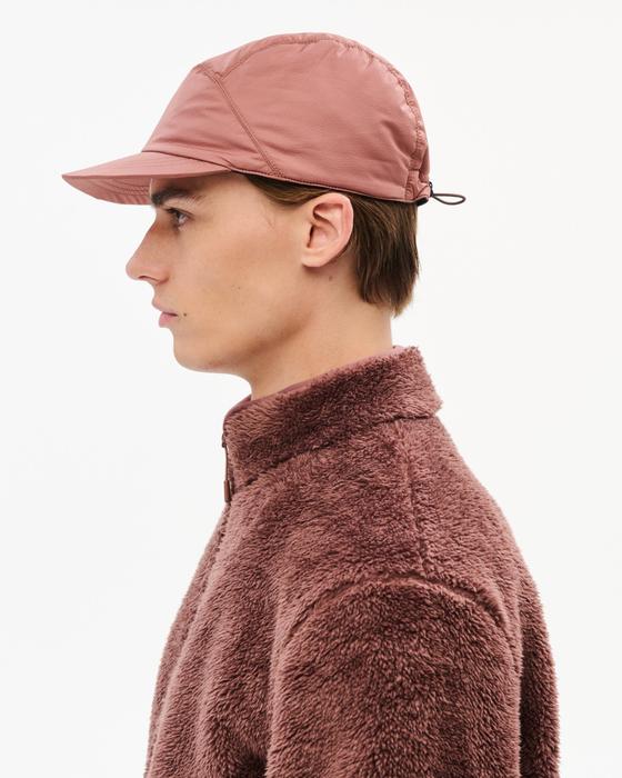 A man wearing a dusty pink Hiking Patrol nylon cap and matching fleece jacket