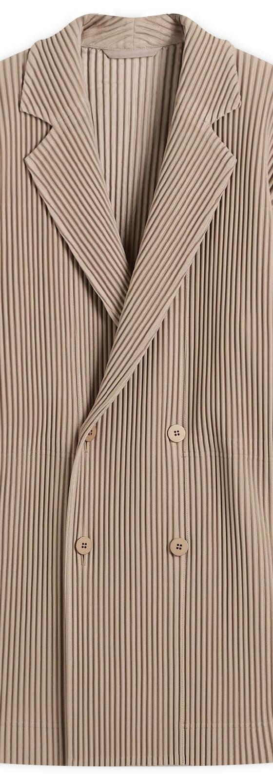 A taupe HOMME PLISSÉ ISSEY MIYAKE pleated double-breasted blazer on a plain background