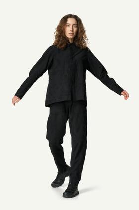 A woman wearing a black Houdini Sportswear overshirt and matching trousers
