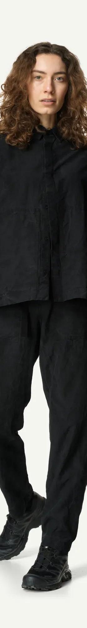 A woman wearing a black Houdini Sportswear overshirt and matching trousers