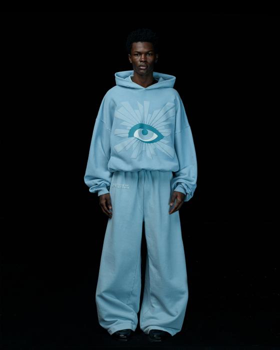 A man wearing a light blue House of Errors All-Seeing hoodie and wide matching trousers