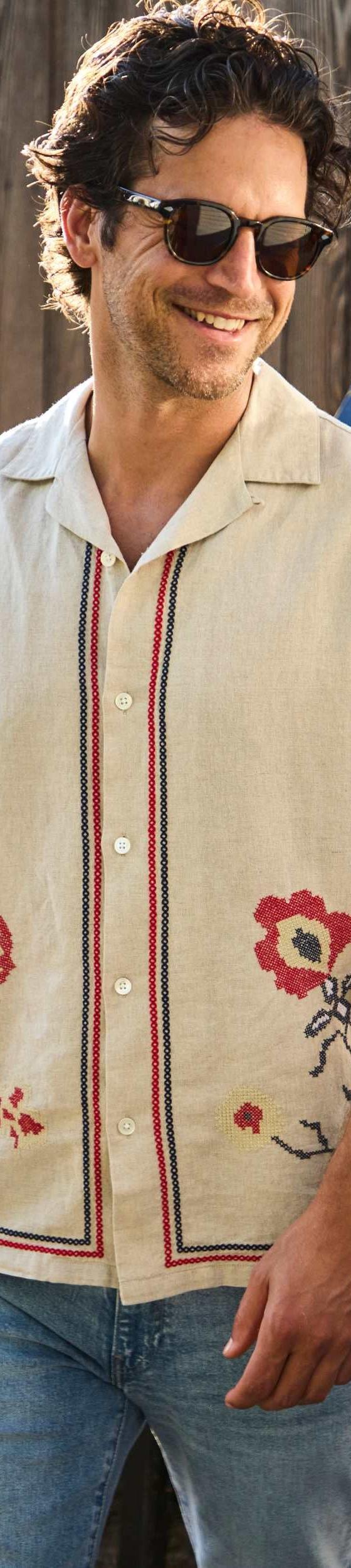A man wearing a cream embroidered floral camp-collar shirt by House of LAND