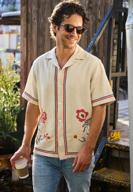 A man wearing a cream embroidered floral camp-collar shirt by House of LAND