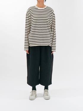 A woman wearing a cream and black striped ICHI long-sleeve tee with wide black cropped trousers