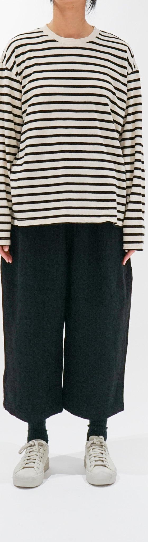 A woman wearing a cream and black striped ICHI long-sleeve tee with wide black cropped trousers