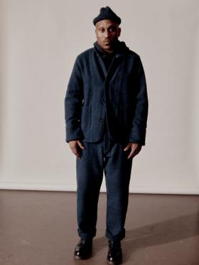 A man wearing a navy Indi + Ash wool chore jacket and matching trousers with a knit beanie