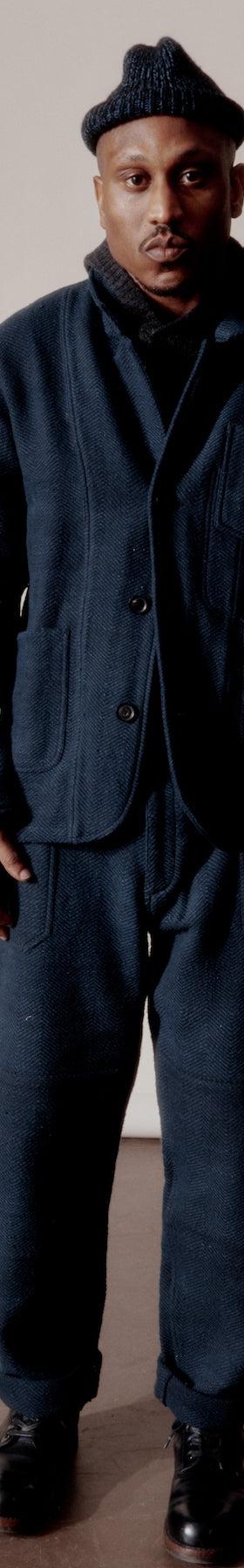A man wearing a navy Indi + Ash wool chore jacket and matching trousers with a knit beanie