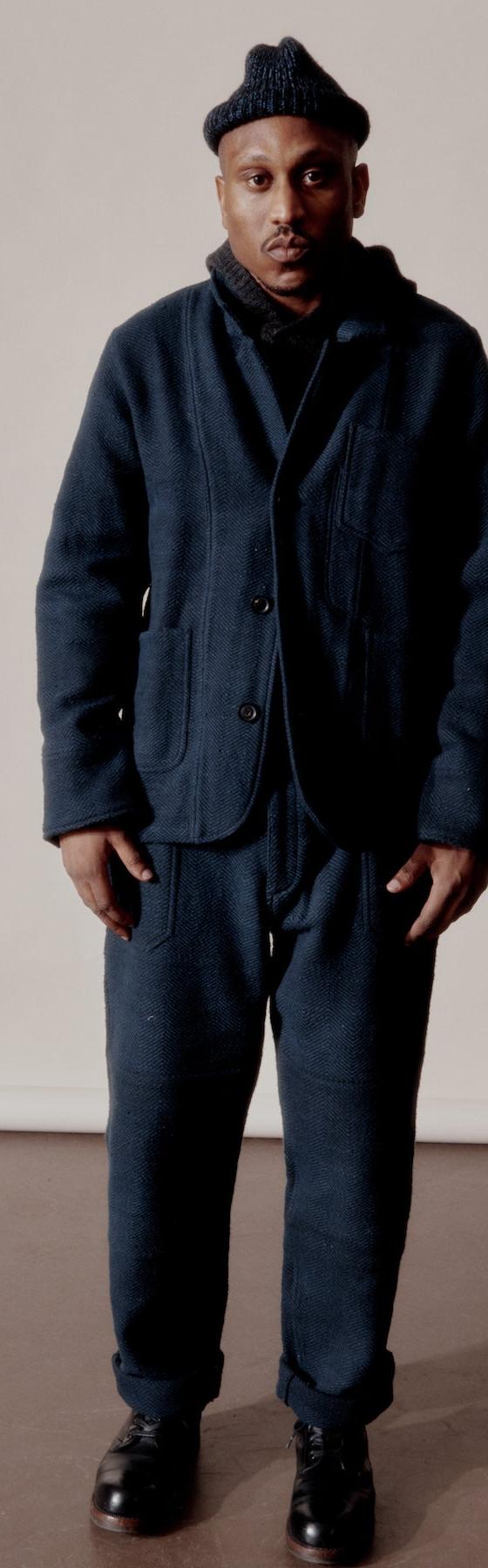 A man wearing a navy Indi + Ash wool chore jacket and matching trousers with a knit beanie
