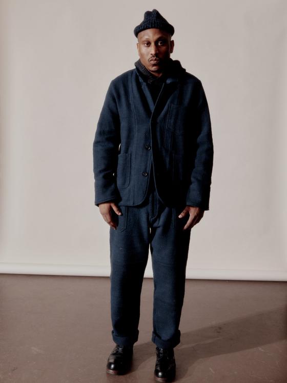 A man wearing a navy Indi + Ash wool chore jacket and matching trousers with a knit beanie