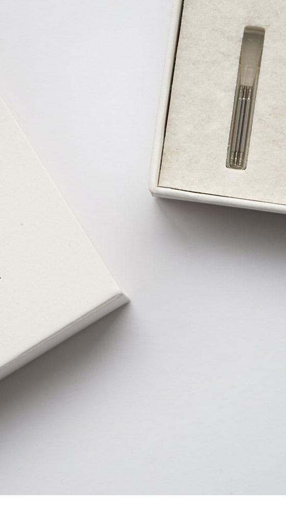 An Instrmnt watch with a white dial and slim steel case presented in its felt-lined box beside a notebook
