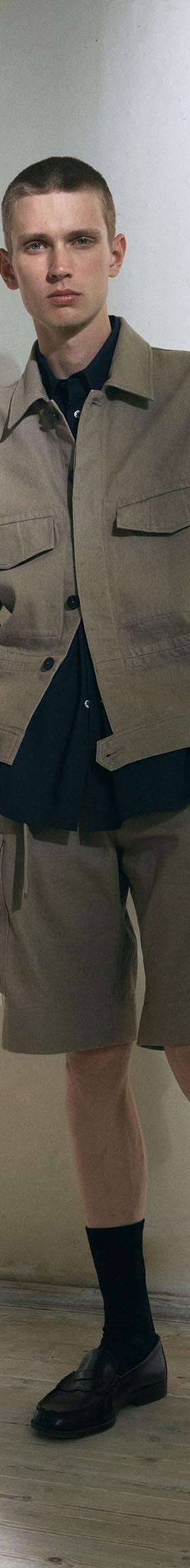 A man wearing a beige Jan Machenhauer utility jacket and matching cargo shorts
