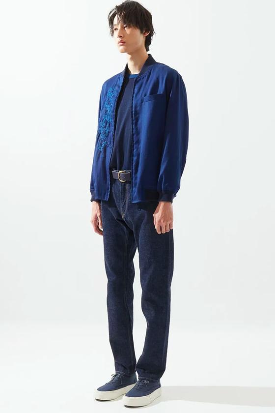 A man wearing an indigo Japan Blue bomber jacket over a navy tee with dark selvedge denim jeans