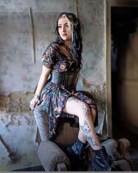A woman wearing a Jawbreaker Clothing floral print dress with a black underbust corset belt and boots