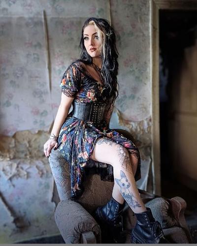 A woman wearing a Jawbreaker Clothing floral print dress with a black underbust corset belt and boots