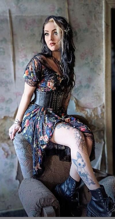 A woman wearing a Jawbreaker Clothing floral print dress with a black underbust corset belt and boots