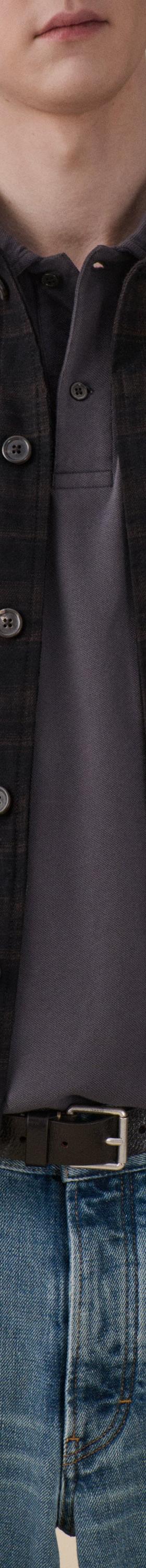 A man wearing a dark checked Jeanerica jacket over a grey polo with blue jeans