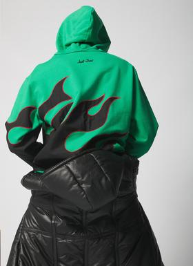 A person wearing a green Just Don hoodie with black flame graphics, seen from behind