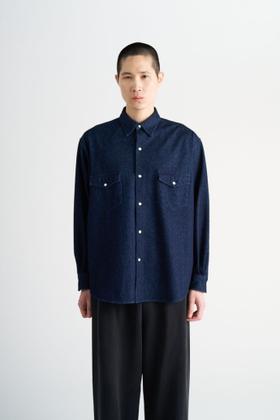 A man wearing a navy KANEMASA PHIL. knit shirt with black wide-leg trousers