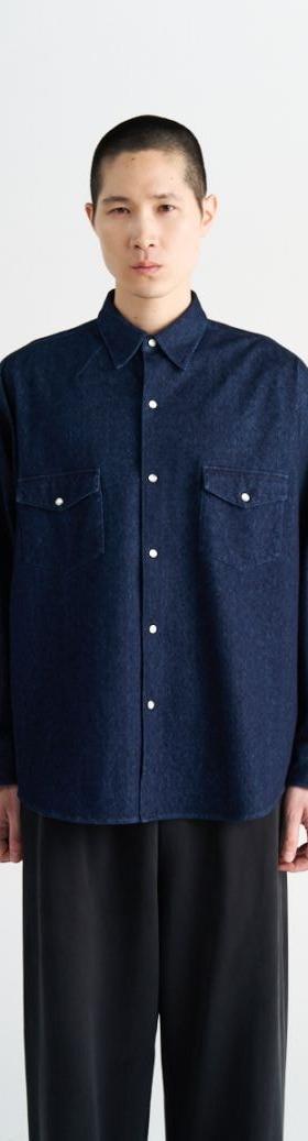 A man wearing a navy KANEMASA PHIL. knit shirt with black wide-leg trousers