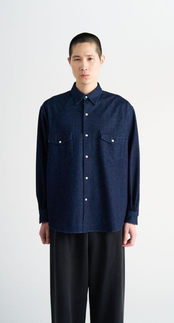 A man wearing a navy KANEMASA PHIL. knit shirt with black wide-leg trousers