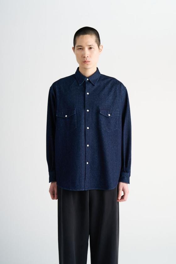 A man wearing a navy KANEMASA PHIL. knit shirt with black wide-leg trousers