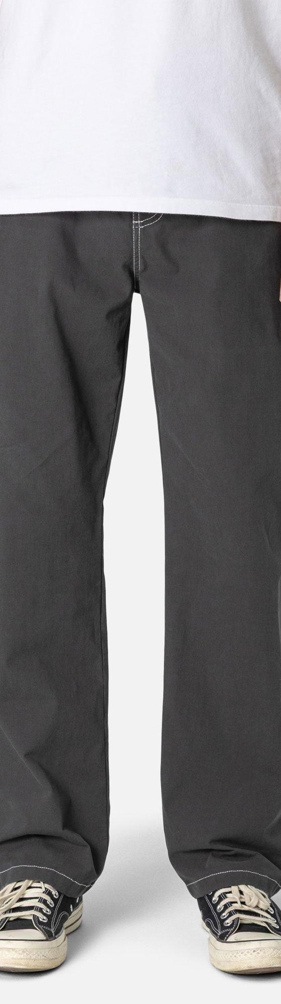 A man wearing charcoal Katin canvas work pants with a white tee and sneakers