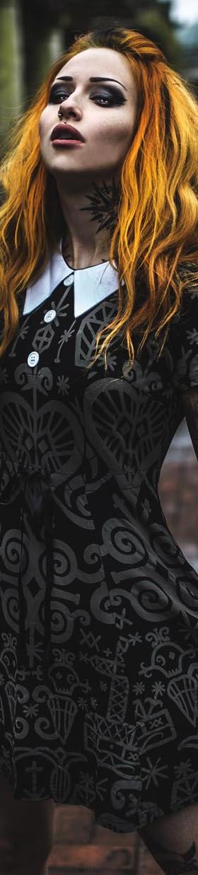 A woman wearing a black occult-print Killstar collared dress in a stone colonnade