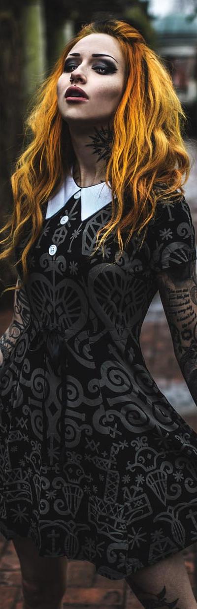 A woman wearing a black occult-print Killstar collared dress in a stone colonnade