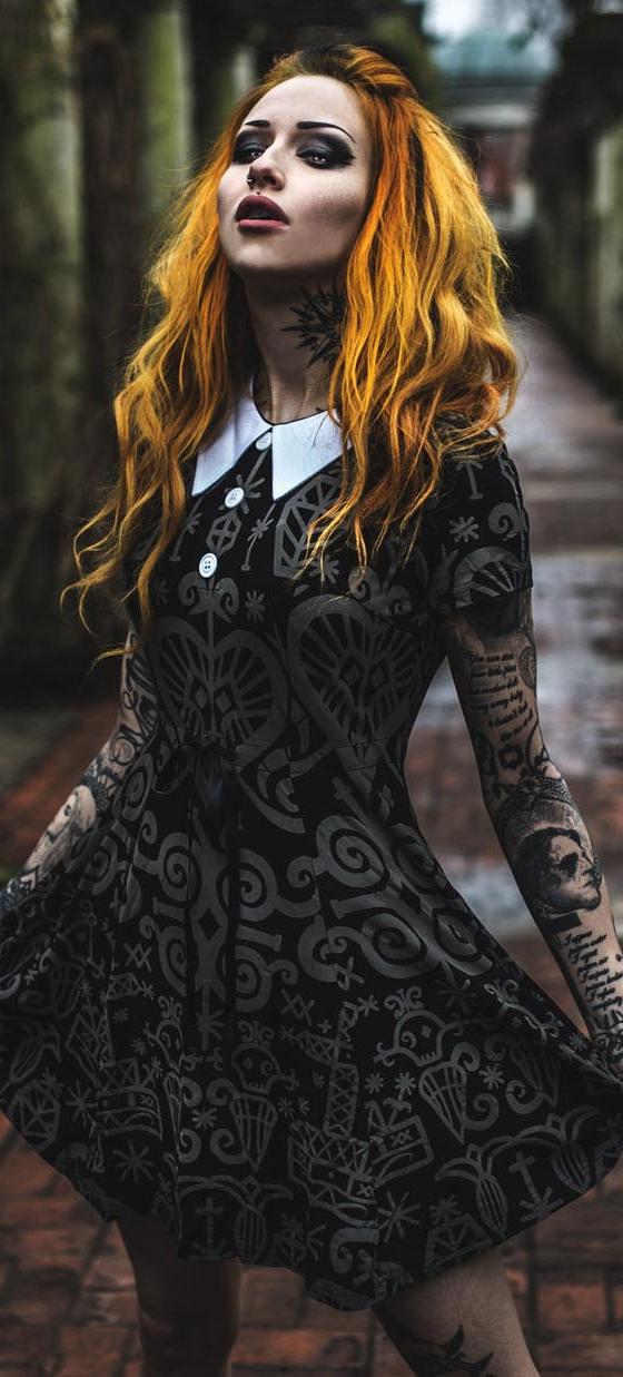 A woman wearing a black occult-print Killstar collared dress in a stone colonnade