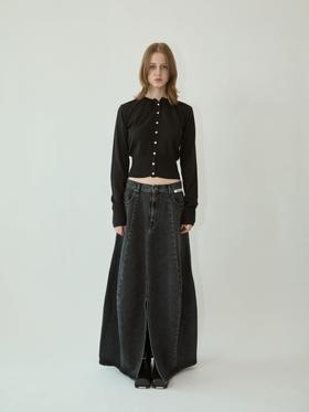 A woman wearing a black KIMHĒKIM cropped cardigan with pearl buttons and a long washed black denim skirt