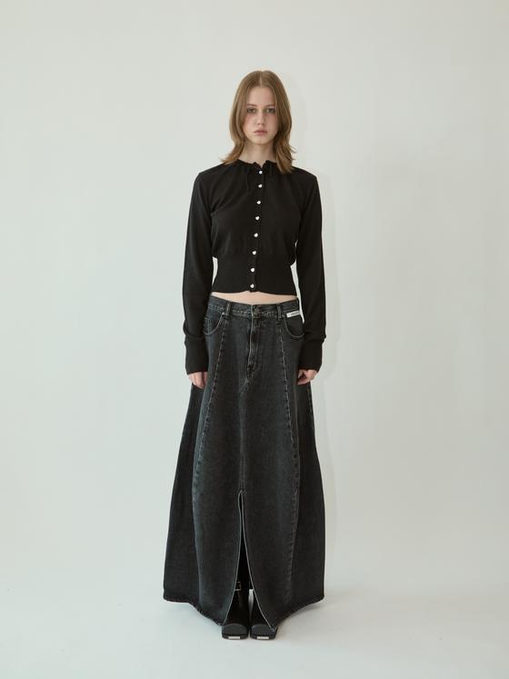 A woman wearing a black KIMHĒKIM cropped cardigan with pearl buttons and a long washed black denim skirt