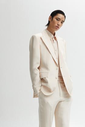 A man wearing a cream KIMSEORYONG peak-lapel suit and shirt