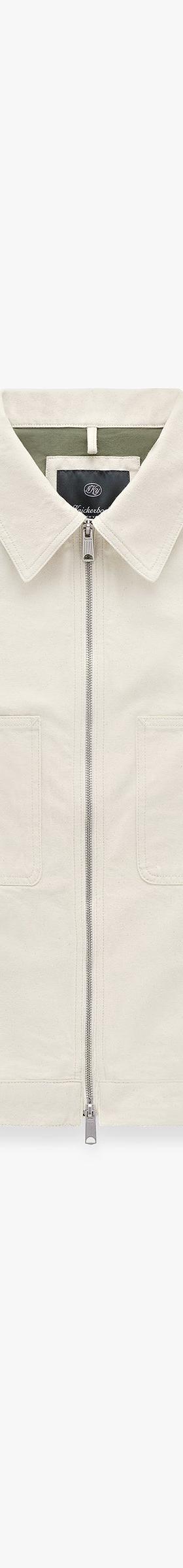 An off-white Knickerbocker zip-front work jacket with flap chest pockets on a plain background