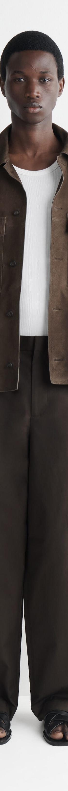 A man wearing a brown suede overshirt with matching wide-leg trousers