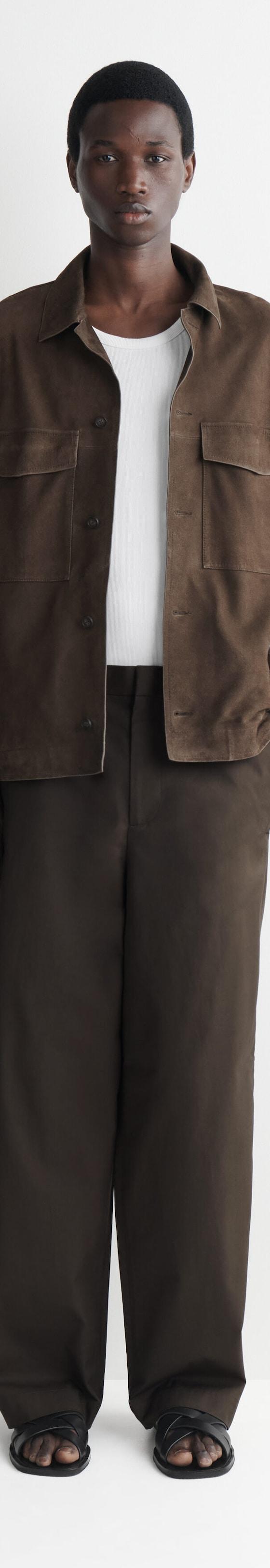 A man wearing a brown suede overshirt with matching wide-leg trousers