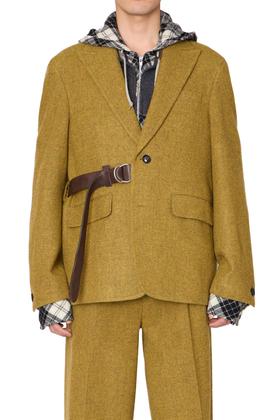 A man wearing a mustard yellow kolor tweed blazer with a leather belt strap and layered check hooded shirt