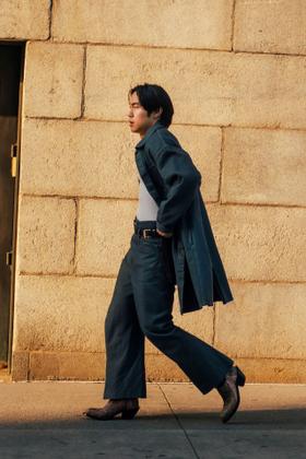A man wearing a Kozaburo indigo denim coat with wide-leg jeans and curved-heel snakeskin boots