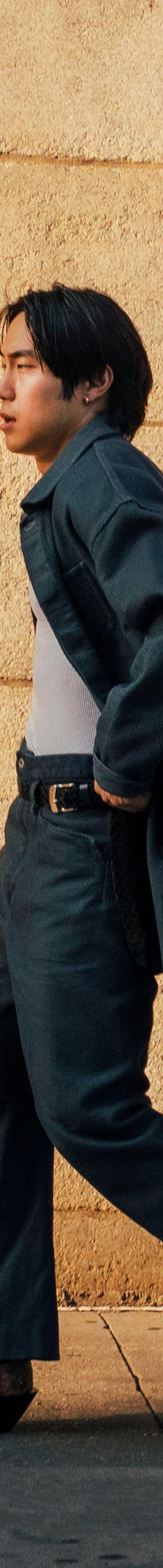 A man wearing a Kozaburo indigo denim coat with wide-leg jeans and curved-heel snakeskin boots