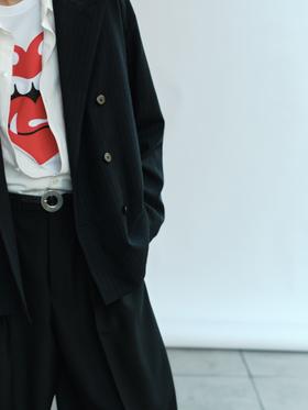 A man wearing a black pinstripe double-breasted LAD MUSICIAN jacket over a white graphic tee with wide trousers