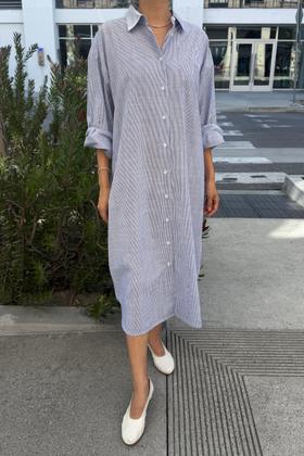 A woman wearing a pale blue striped Le Bon Shoppe shirt dress with white flats