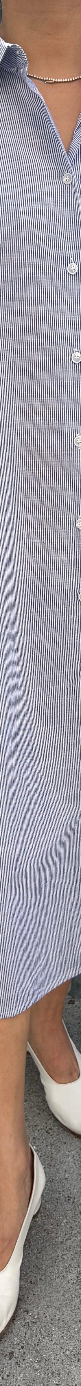 A woman wearing a pale blue striped Le Bon Shoppe shirt dress with white flats