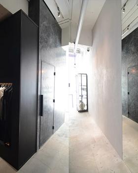 Lift Daikanyama interior: black display cubes with hanging garments, raw grey walls, gallery lighting, no people