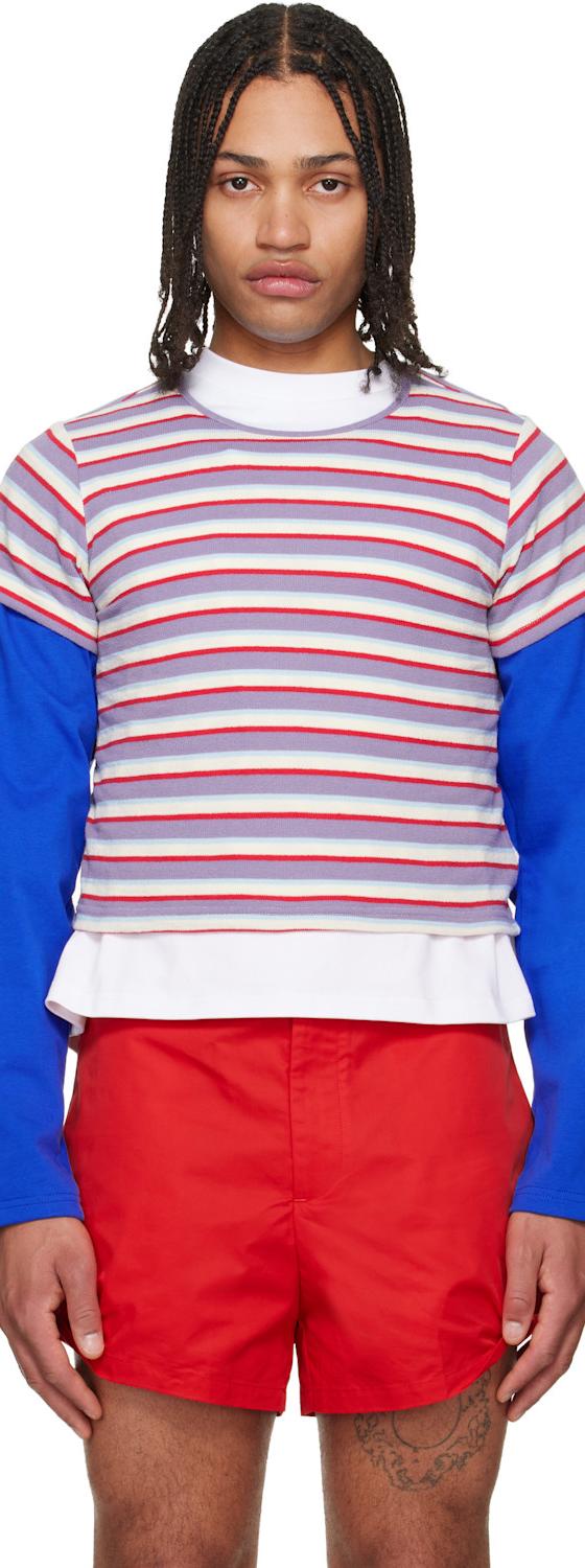 A man wearing a striped LII layered top with blue sleeves and red shorts