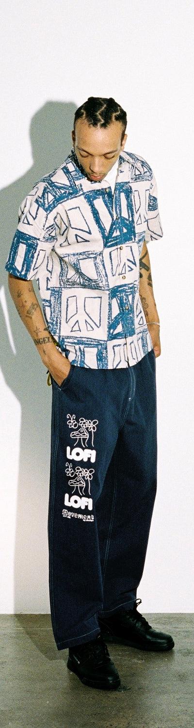 A man wearing a blue-printed Lo-fi camp-collar shirt with wide dark denim jeans